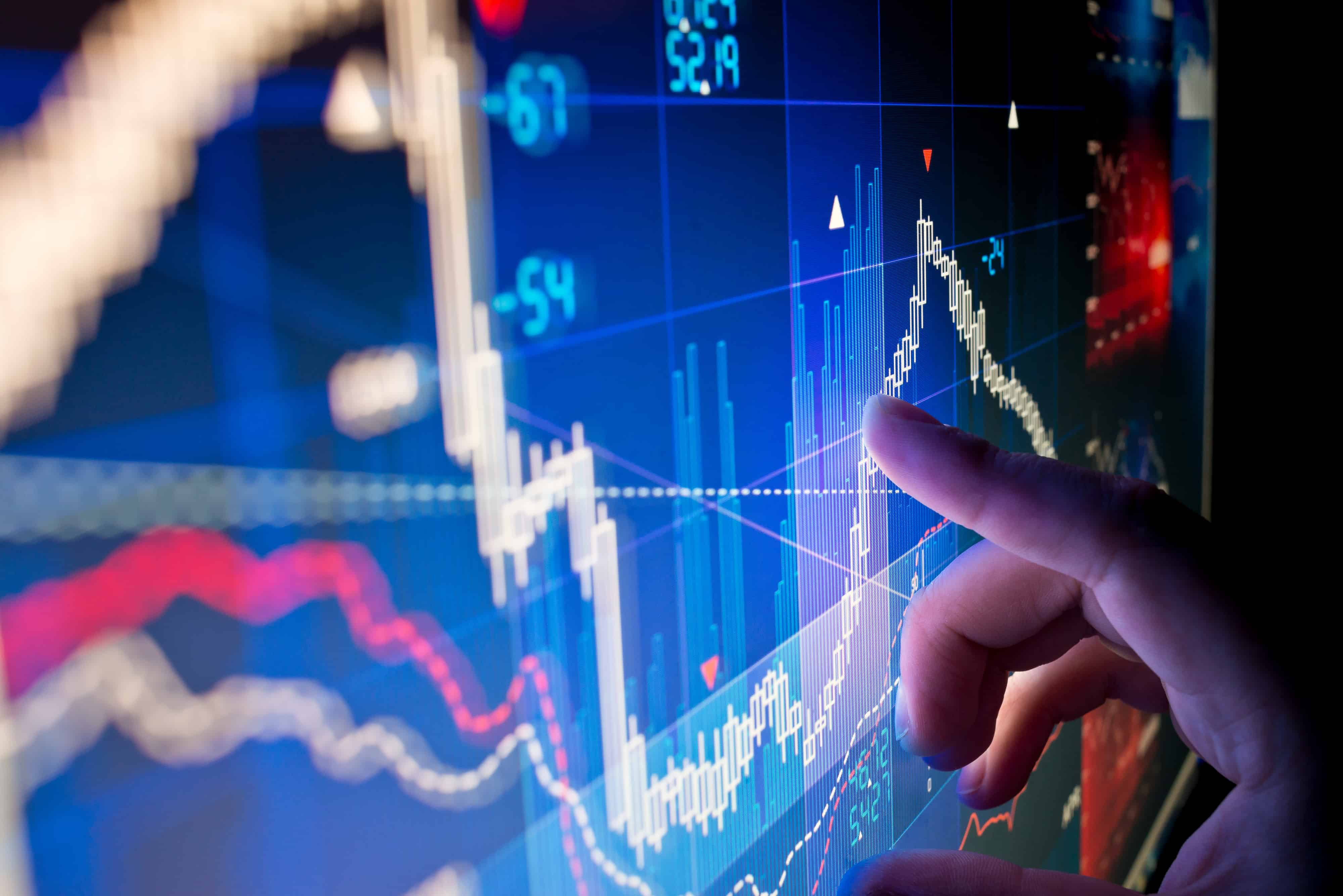 Business analyst analysising market data on a monitor.