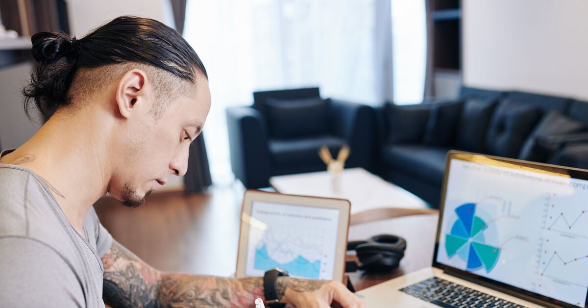 A man seated in front of his laptop writing and wondering are online degrees respected by employers