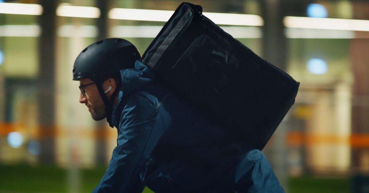 A delivery man on his bicycle carries a big delivery bag on his back, experiencing data science applied to business.