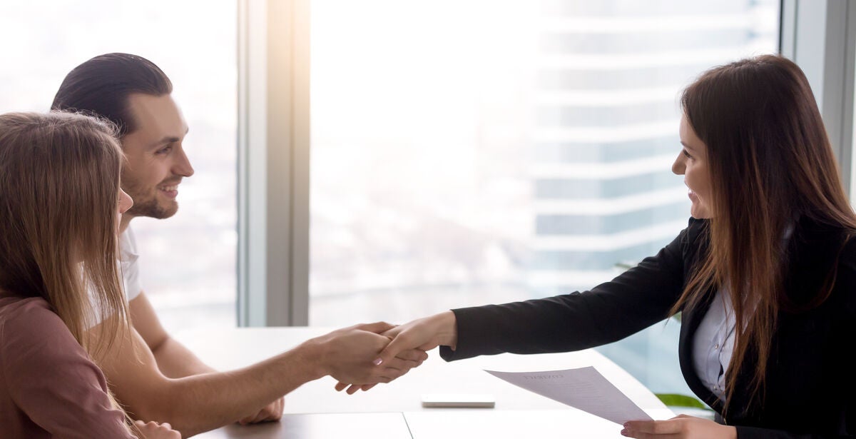 A professional woman shakes hands with a graduate who asks ‘does an MBA increase salary potential?’.