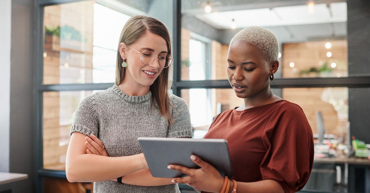 Two female colleagues looking on a tablet on how is ai changing digital marketing