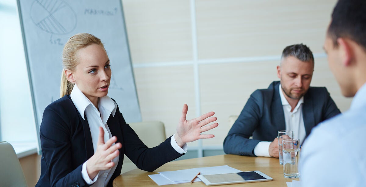 A woman sitting between two men with a tablet, discussing how to become a CFO.