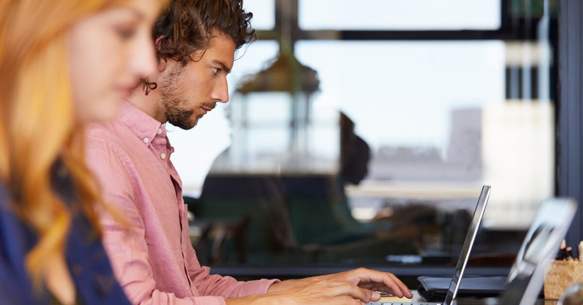 A woman and a man working on their laptops as they search is automation the future of digital marketing