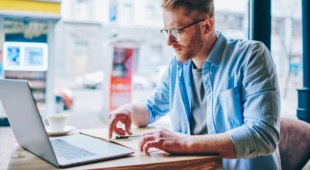 A male MBA student studying on his laptop in a cafe.