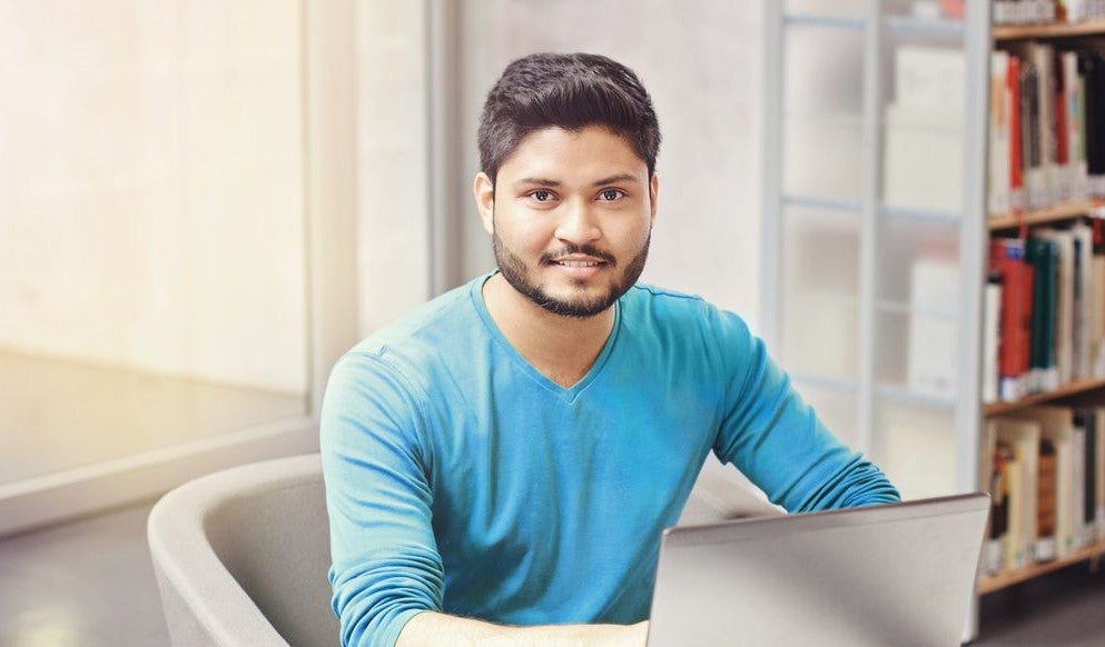 Man in a blue shirt studying in a library